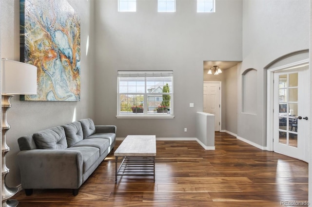living room with baseboards, wood finished floors, and a towering ceiling