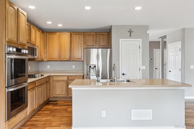 kitchen with appliances with stainless steel finishes, a sink, light wood-style floors, light countertops, and visible vents