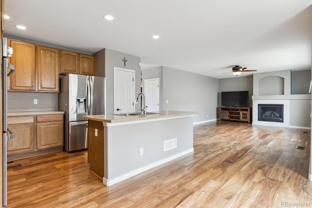 kitchen with stainless steel fridge, a sink, light wood-style floors, light countertops, and a ceiling fan