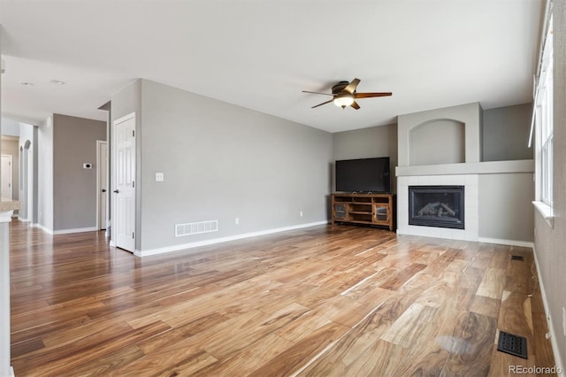 unfurnished living room with visible vents, light wood-style flooring, and a tile fireplace