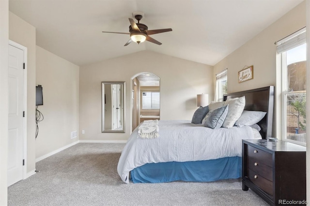 carpeted bedroom with arched walkways, baseboards, vaulted ceiling, and ceiling fan