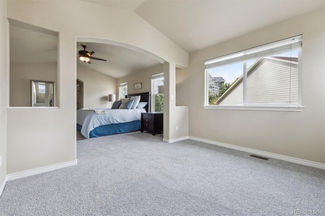 carpeted bedroom with arched walkways, baseboards, visible vents, and lofted ceiling