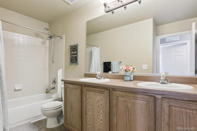bathroom with double vanity, toilet, a sink, and tile patterned flooring
