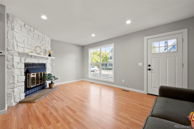 entryway with a stone fireplace and wood-type flooring