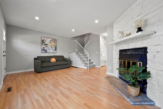 living room with wood-type flooring and a stone fireplace