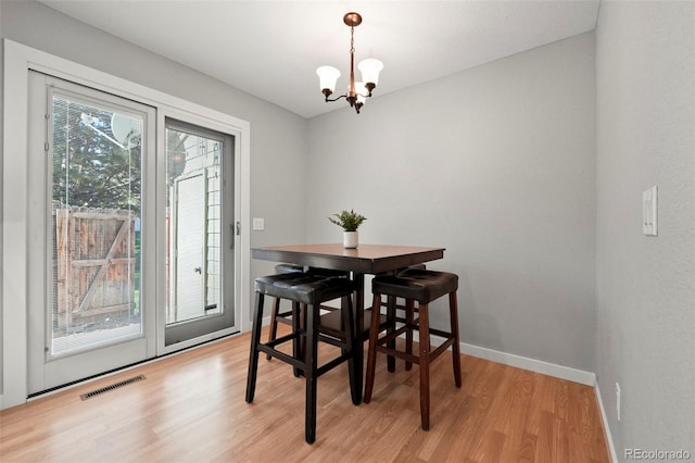 dining area with light wood-type flooring and a notable chandelier