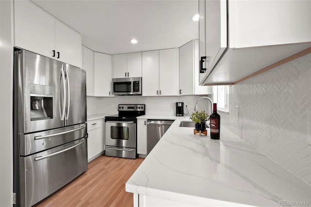 kitchen with white cabinetry, light stone countertops, sink, and appliances with stainless steel finishes