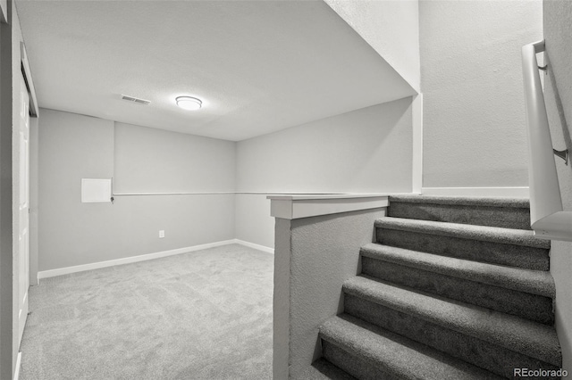 staircase with carpet flooring and a textured ceiling