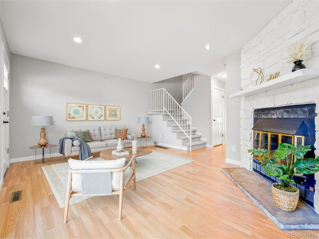 living room with a stone fireplace and light wood-type flooring