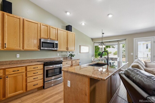 2169 Fox Fire St, Highlands Ranch, CO 80129 - kitchen featuring appliances with stainless steel finishes, lofted ceiling, light wood finished floors, light stone counters, and a center island with sink