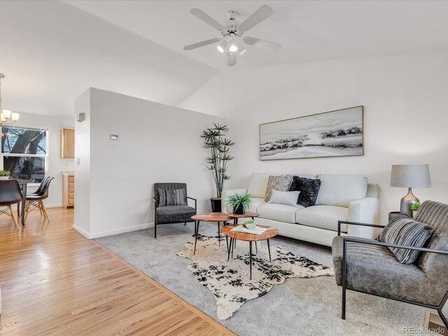 living room with ceiling fan with notable chandelier, lofted ceiling, and light hardwood / wood-style floors