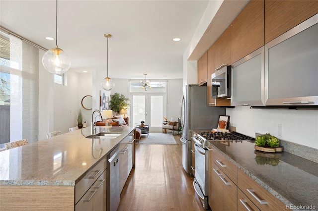 kitchen featuring sink, hardwood / wood-style flooring, a large island, stainless steel appliances, and light stone countertops