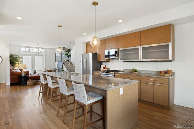 kitchen with sink, dark wood-type flooring, a center island with sink, and appliances with stainless steel finishes