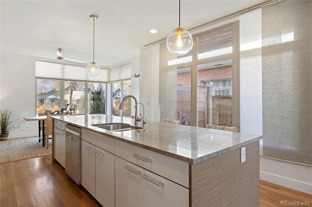 kitchen with decorative light fixtures, dishwasher, white cabinetry, sink, and an island with sink