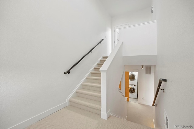 staircase featuring stacked washer / drying machine and carpet floors