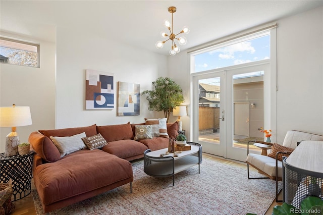 living area with wood finished floors, a wealth of natural light, and a notable chandelier