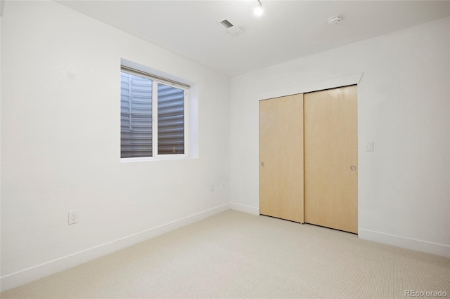 unfurnished bedroom with light carpet, baseboards, visible vents, and a closet