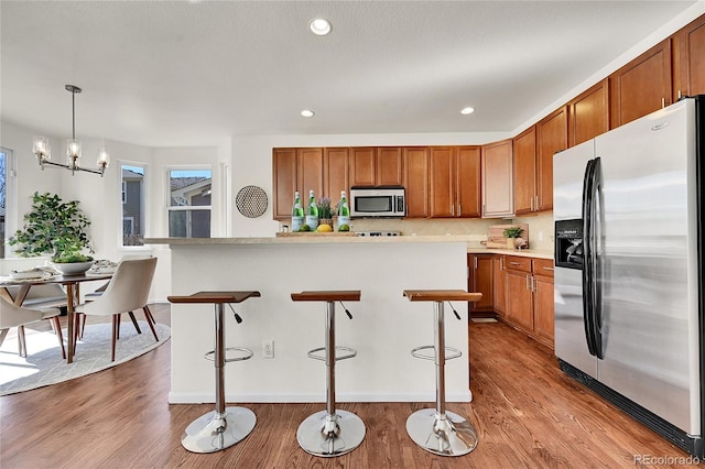 kitchen featuring appliances with stainless steel finishes, wood finished floors, and brown cabinets