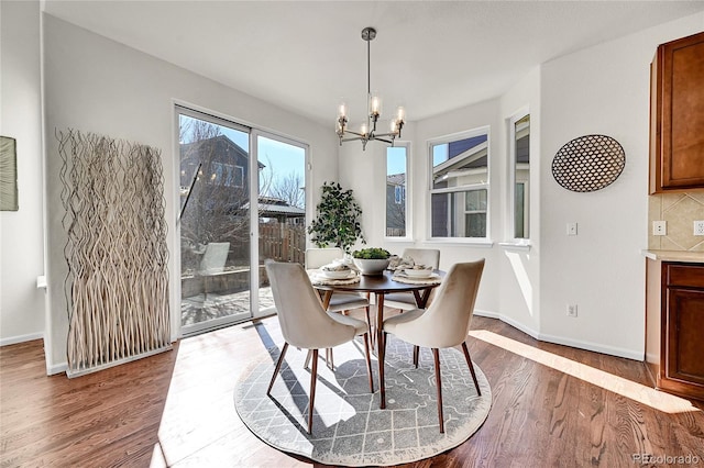 dining area featuring a chandelier, baseboards, and wood finished floors