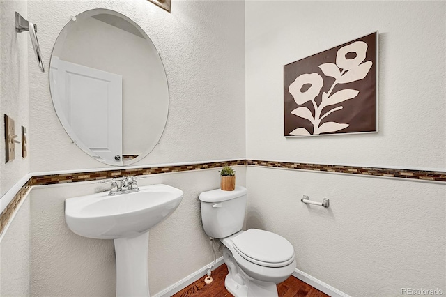 bathroom featuring toilet, baseboards, and wood finished floors