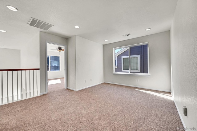 carpeted spare room featuring baseboards, visible vents, and recessed lighting