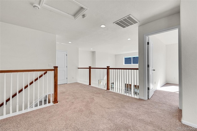 hall with recessed lighting, visible vents, attic access, carpet flooring, and an upstairs landing