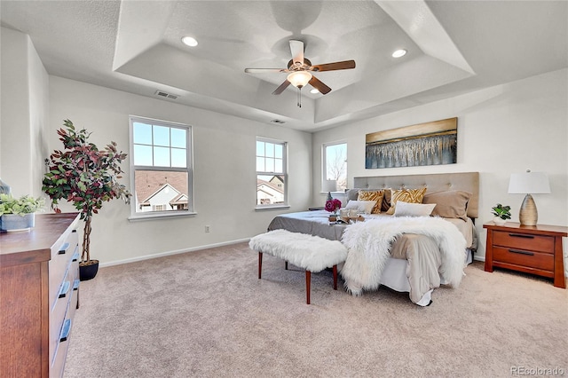 bedroom with a raised ceiling, visible vents, baseboards, and carpet flooring