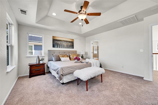 carpeted bedroom featuring baseboards, visible vents, a raised ceiling, and recessed lighting