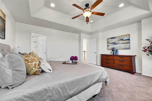 bedroom with recessed lighting, baseboards, a tray ceiling, and light colored carpet