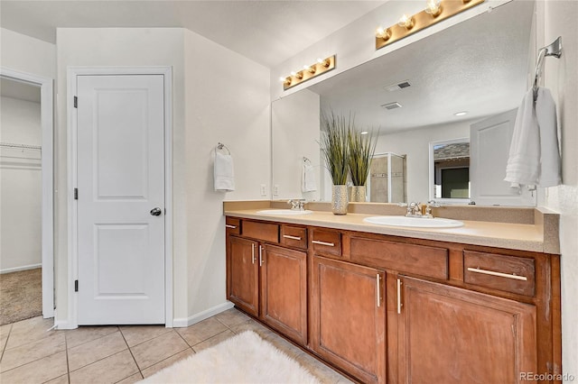 full bathroom featuring tile patterned flooring, visible vents, a sink, and a shower stall