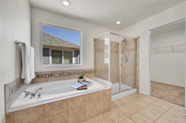 full bath featuring tile patterned flooring, recessed lighting, a shower stall, a bath, and a walk in closet