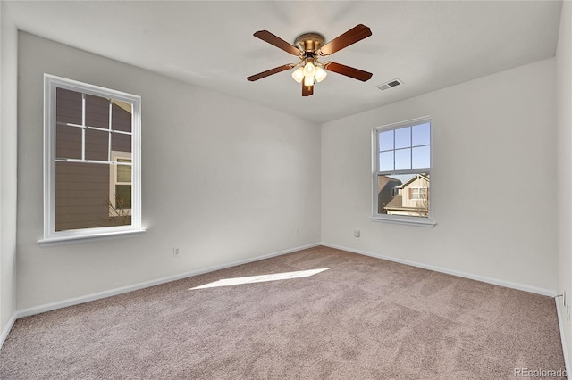 carpeted spare room featuring ceiling fan, visible vents, and baseboards