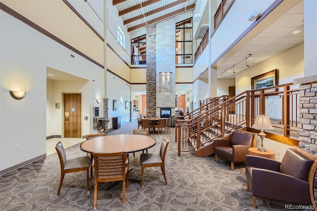 3184 S Heather Gardens Way Unit 302, Aurora, CO 80014 - carpeted dining room featuring a towering ceiling, stairs, a fireplace, and decorative columns