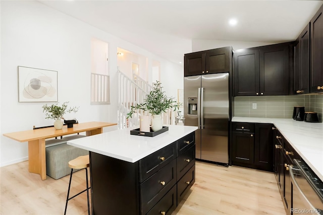 129 Gordon Pl, Castle Rock, CO 80104 - kitchen with a breakfast bar, light wood-type flooring, light countertops, tasteful backsplash, and appliances with stainless steel finishes