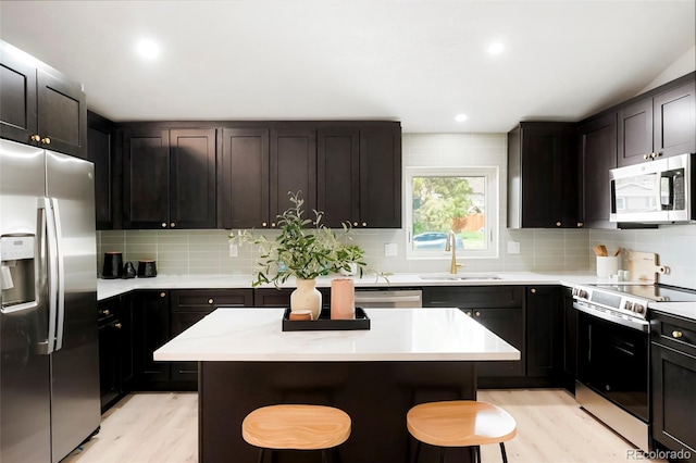 129 Gordon Pl, Castle Rock, CO 80104 - kitchen with a sink, light wood finished floors, appliances with stainless steel finishes, and a breakfast bar area