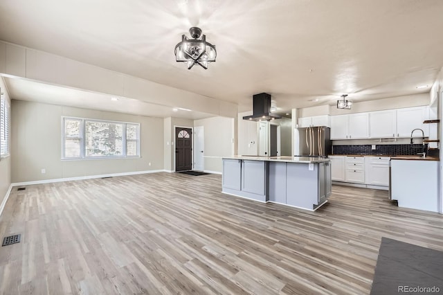 kitchen with freestanding refrigerator, open floor plan, island range hood, light wood-type flooring, and visible vents