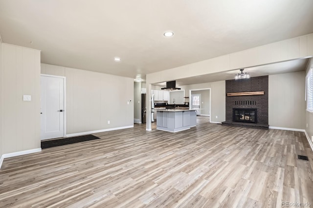 unfurnished living room featuring baseboards, a fireplace, light wood-style flooring, and visible vents