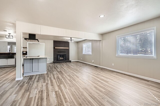 unfurnished living room with a fireplace, recessed lighting, baseboards, and light wood-style floors