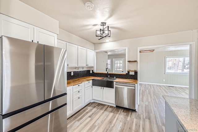 kitchen featuring a sink, appliances with stainless steel finishes, plenty of natural light, and light wood-style flooring