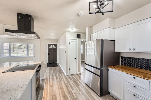 kitchen with butcher block countertops, range with electric stovetop, light wood-type flooring, freestanding refrigerator, and extractor fan
