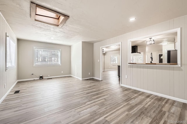 unfurnished living room with baseboards, wood finished floors, and visible vents