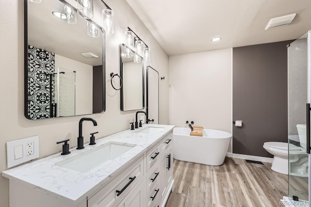 bathroom featuring a sink, wood finished floors, toilet, and a soaking tub
