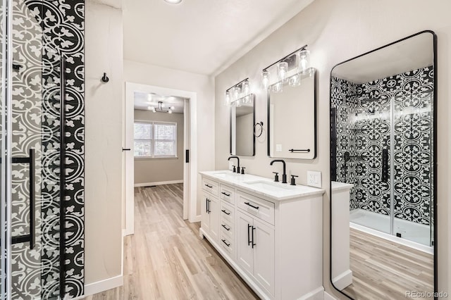 bathroom featuring a sink, double vanity, wood finished floors, and a notable chandelier