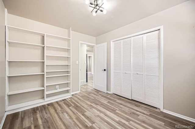 unfurnished bedroom featuring baseboards, wood finished floors, and a closet