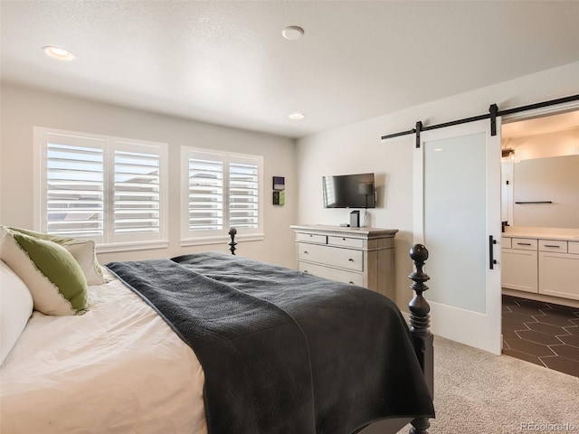 carpeted bedroom with ensuite bath and a barn door