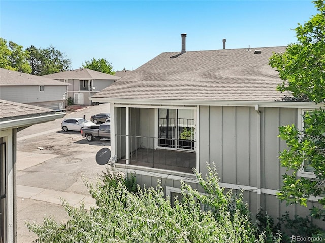 14590 E 13th Ave, Aurora, CO 80011 - rear view of house featuring a shingled roof, board and batten siding, and uncovered parking