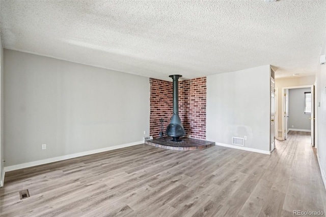 14590 E 13th Ave, Aurora, CO 80011 - unfurnished living room with a textured ceiling, wood finished floors, and a wood stove
