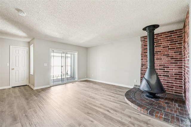 14590 E 13th Ave, Aurora, CO 80011 - unfurnished living room with wood finished floors, a wood stove, and a textured ceiling