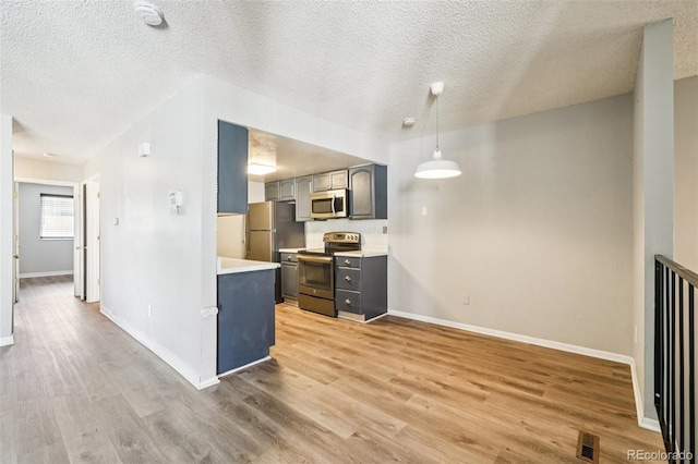 14590 E 13th Ave, Aurora, CO 80011 - kitchen featuring stainless steel appliances, light wood finished floors, a textured ceiling, gray cabinets, and light countertops