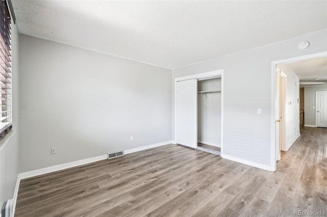 14590 E 13th Ave, Aurora, CO 80011 - unfurnished bedroom with light wood-type flooring, a closet, and a textured ceiling